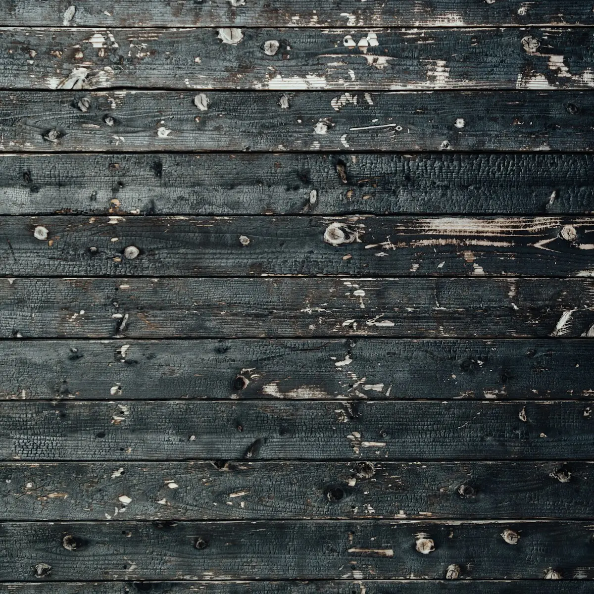 Deep-charred black timber boards, dark crackled burn