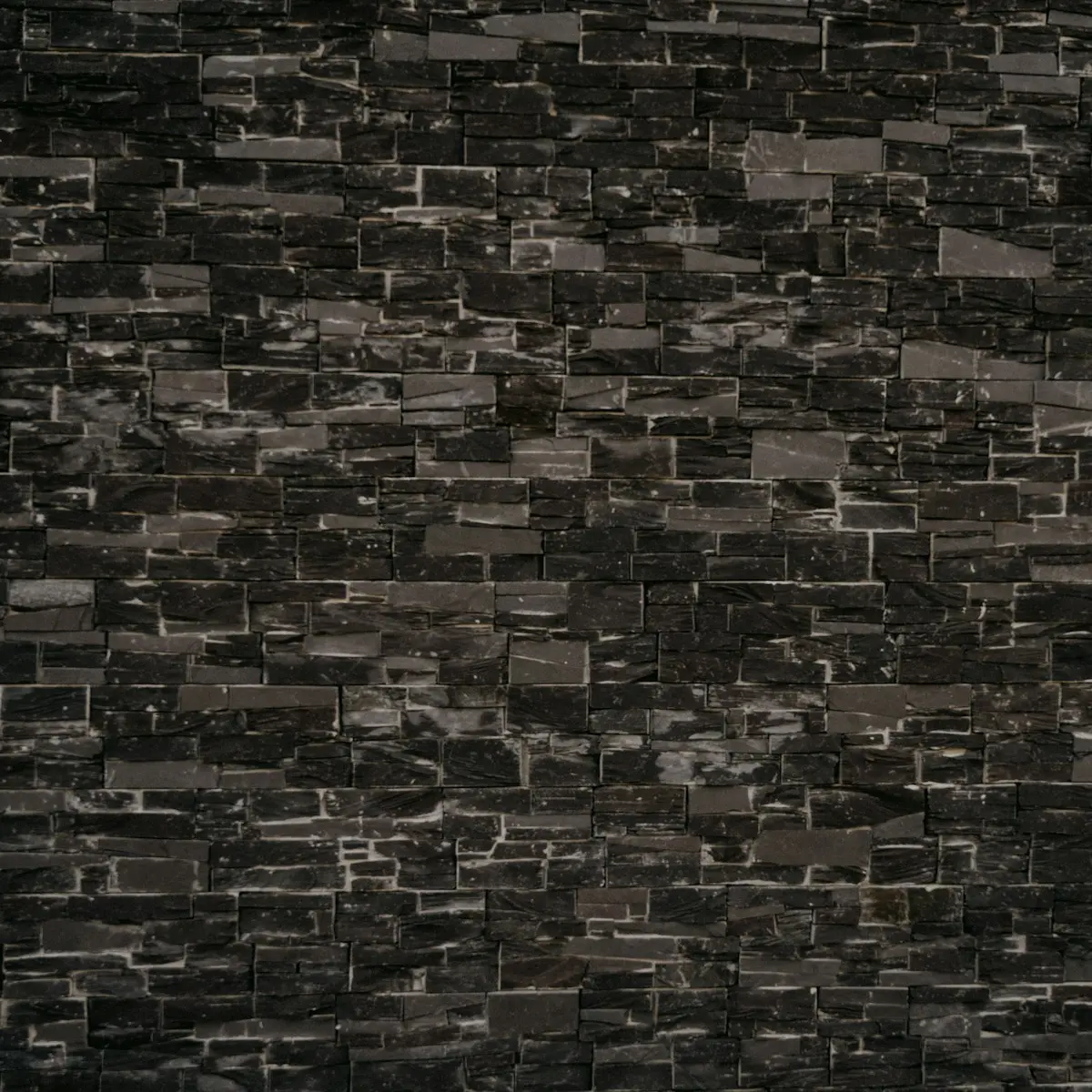Slimline black brick wall laid in black mortar, dark joints