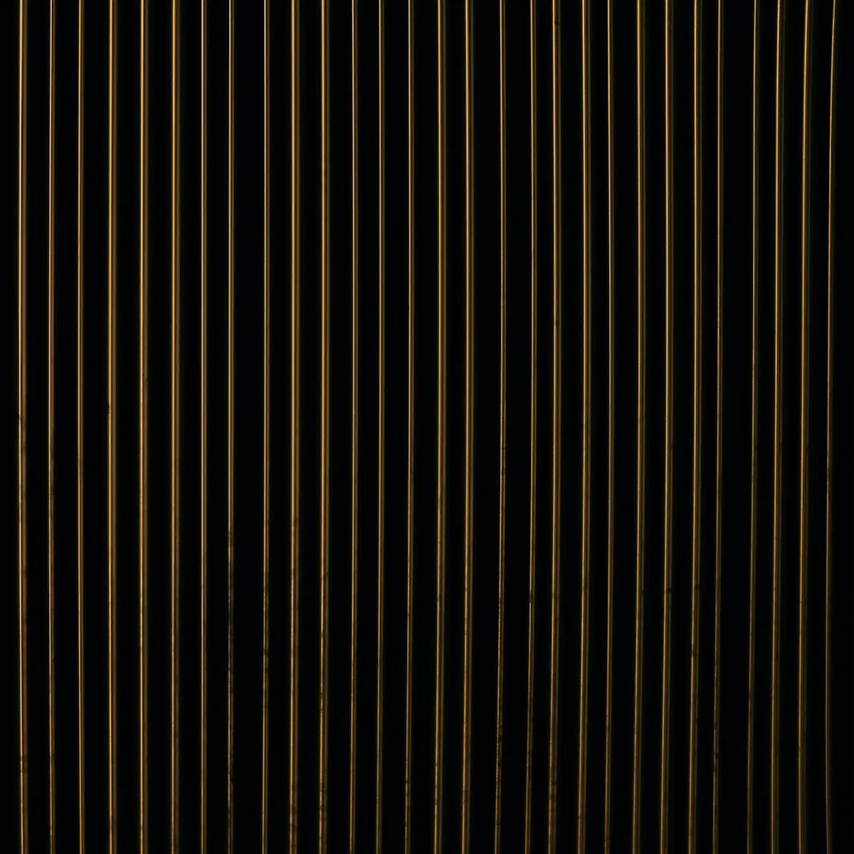 Fluted black panel, fine vertical ribs catching low light